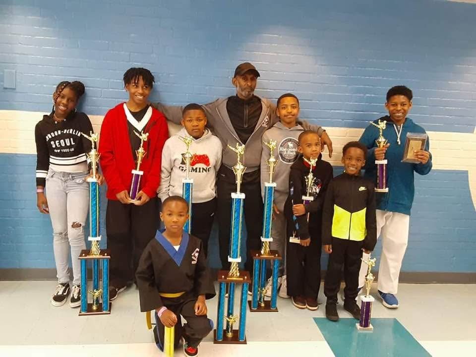 Alpha & Omega students and instructor with tournament trophies